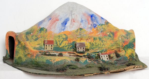 Lionel prewar O gauge tunnel: Lionel prewar O gauge tunnel that measures approximately 31 inches wide, 22 inches deep and 13 inches tall. Tunnel has the houses and shrubs. Corrugated paperboard base. Unmarked.