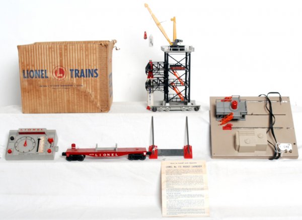 Boxed postwar Lionel No. 175 rocket launcher: Boxed postwar Lionel No. 175 rocket launcher with platform, derrick tower, control panel, 6175 flatcar and missile. Missile is missing foam tip and body is cracked. Derrick tower has one cracked hand 