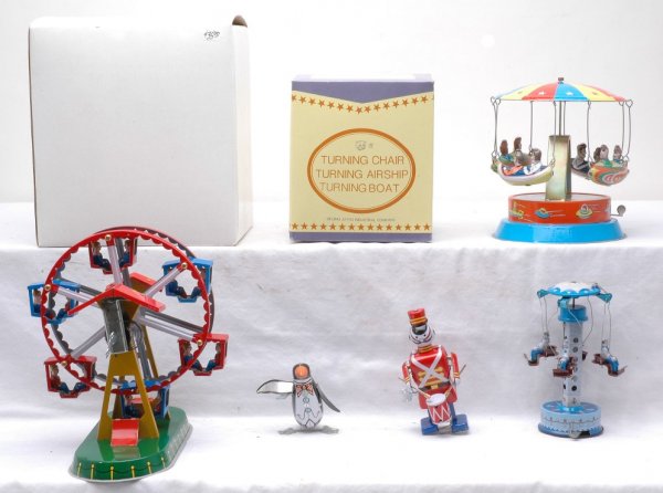 Assortment of Wind-Up Tin Toys and Figures: An assortment of wind-up tin lithographed circus rides including; turning boats, turning chairs and a Ferris Wheel. There is an OB for the Ferris Wheel and Turning Chairs. Also included are two wind-u