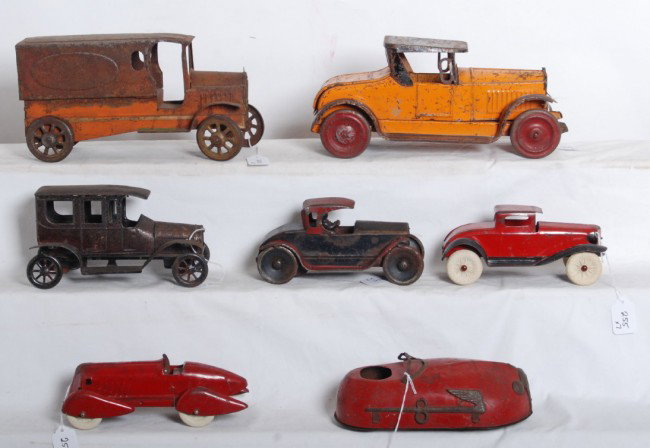 Seven very early tinplate/pressed steel vehicles: Large lot of very early tinplate and pressed steel cars and trucks. Some are key wind mechanical, two appear to have had electric head lights. Two cars are flywheel driven. All are unmarked. Some have