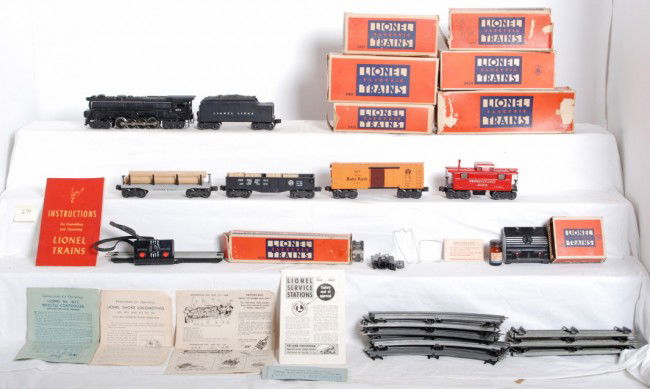 Lionel 671, 671W, X2454, 2452, 2411, 2457 in OB: Postwar Lionel O gauge No. 671 loco, 671W whistle tender, X2454 Pennsylvania Baby Ruth boxcar, 2452 gondola with four wooden barrels, 2411 flatcar with logs, and 2457 Pennsylvania caboose, in original