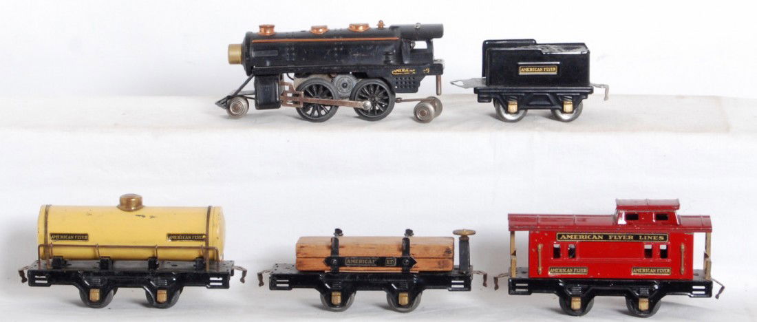American Flyer steam loco, tender, four wheel frei: Prewar American Flyer O gauge tinplate electrical steam locomotive and tender, flatcar with lumber load and original load restraints, tank car, and caboose, C6. Loco has missing drive wheel, casting f