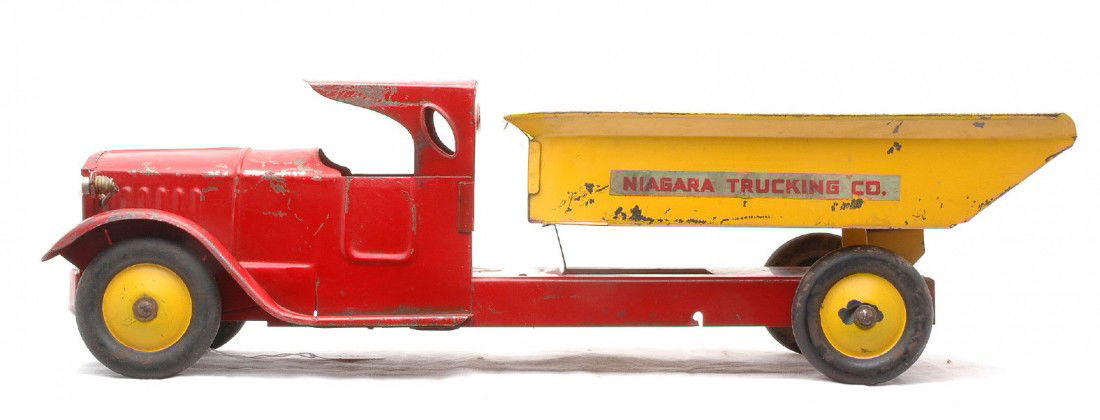 Structo Niagara Trucking Co. Dump Truck: Structo pressed steel red and yellow dump truck with NIAGARA TRUCKING CO. decals on the side of the dump mechanism. The truck measures 21 1/2 inches in length and has rubber tires. The truck is C5.