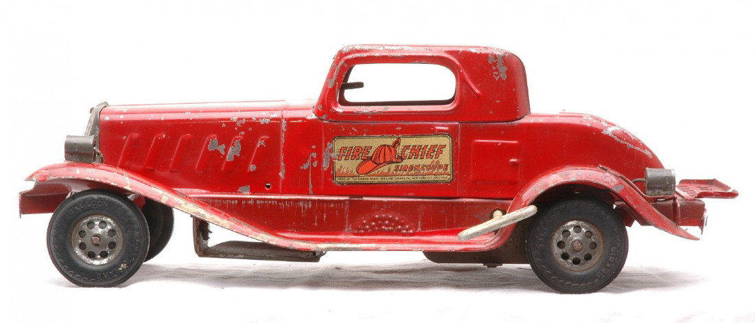 Girard Red Fire Chief Wind Up Siren Coupe: Girard pressed steel red Fire Chief wind up siren coupe that measures 13 1/2 inches in length and has rubber tires. The car is C5.