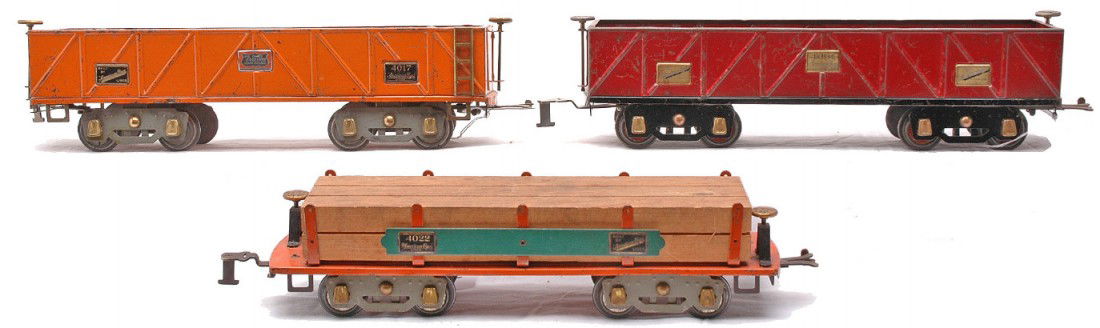 Am Flyer Freight Cars 4007 4007 4022: American Flyer prewar wide gauge freight cars including; 4007 maroon sand car with black frame and flex trucks. Also included is a 4007 orange sand car and a 4022 orange machinery car with wood load b