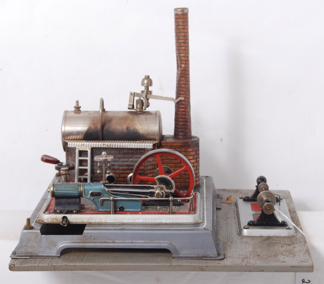 Unmarked steam engine and pulleys mounted on base: Unmarked steam engine and pulleys mounted on wooden base. Boiler has been fired, power transfer section is run, and pulleys have been used. Chimney is bent, glass boiler front is detached, oily, etc. 