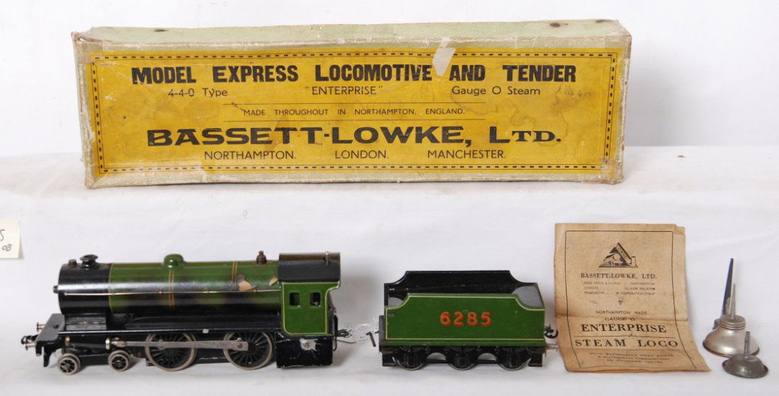 Bassett-Lowke 4-4-0 live steam locomotive: Bassett-Lowke 4-4-0 O gauge live steam locomotive in OB. Loco includes instruction sheet, oiler can, and funnel. Loco is C6 with paint cracking and lifting on the top of the boiler and some signs of b