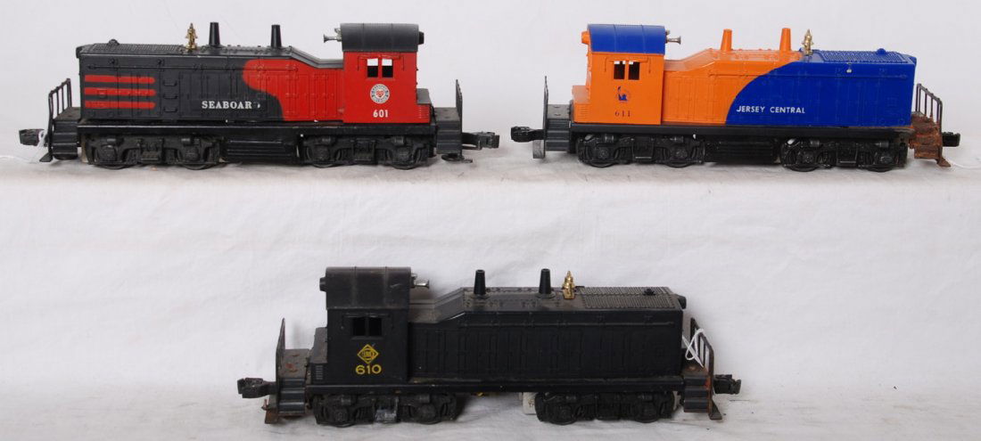Lionel 601, 610, 611 NW2 diesel switcher locos: Postwar Lionel O gauge NW2 diesel locomotive switchers, 601 Seaboard, 610 Erie, and 611 Jersey Central. 601 has repairs at screw, 610 has hairline at nose and rust on frame, and 611 has rusted frame.