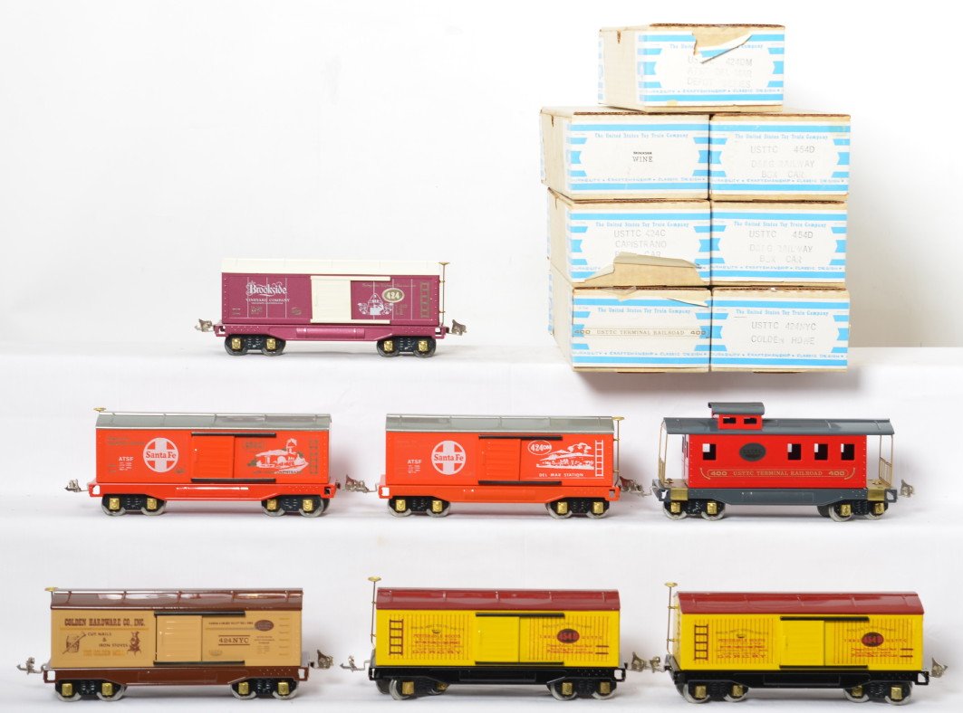 7 USTTC tinplate freight cars: Unites States Toy Train Company modern tinplate freight cars in OBs. Seven cars include two 454D Rio Grande boxcars, 400 U.S.S.T.T.C. terminal caboose, 424NYC Golden Hardware boxcar, 424DM Santa Fe De