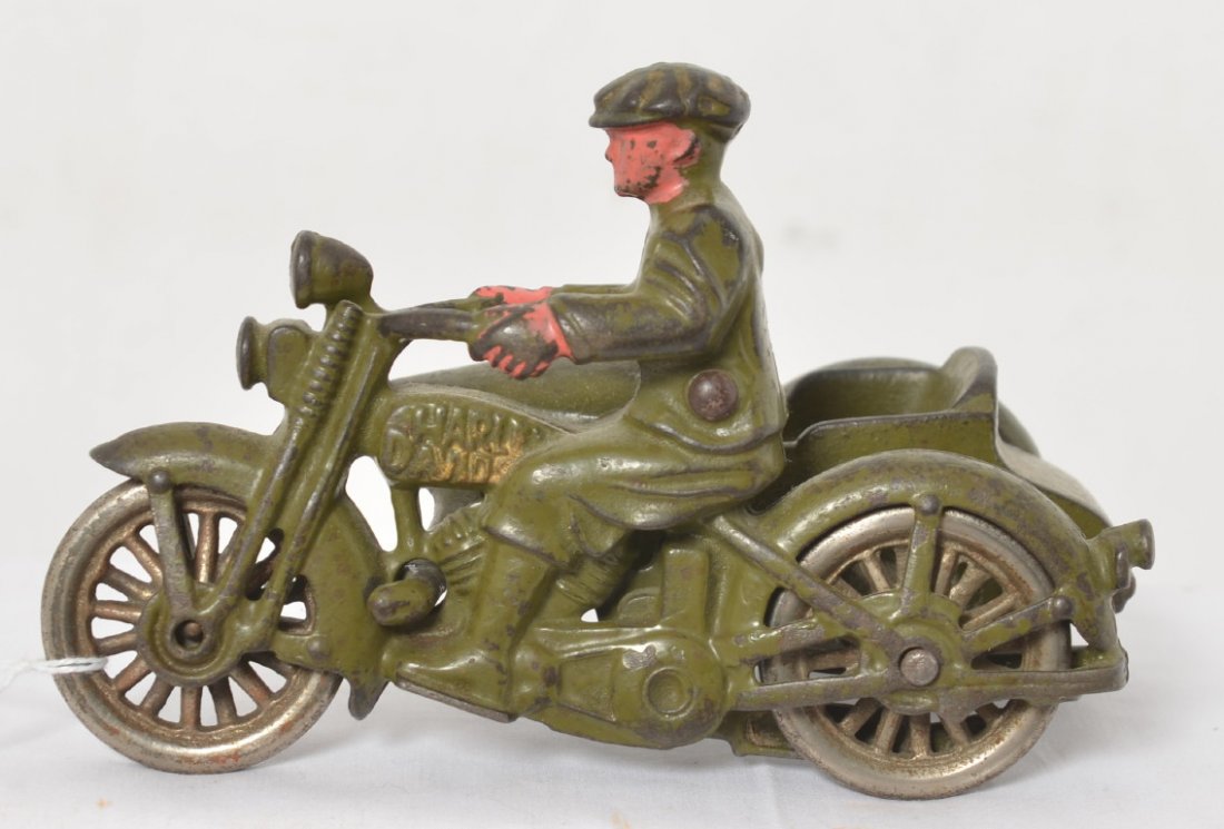 Cast iron Harley Davidson motorcycle with sidecar: Cast iron Harley-Davidson motorcycle with side car. Rider has a cap and short pants. Bike is twin cylinder with muffler and shark fin exhaust tip. Detail shows bicycle pedal kick starter. Sidecar has