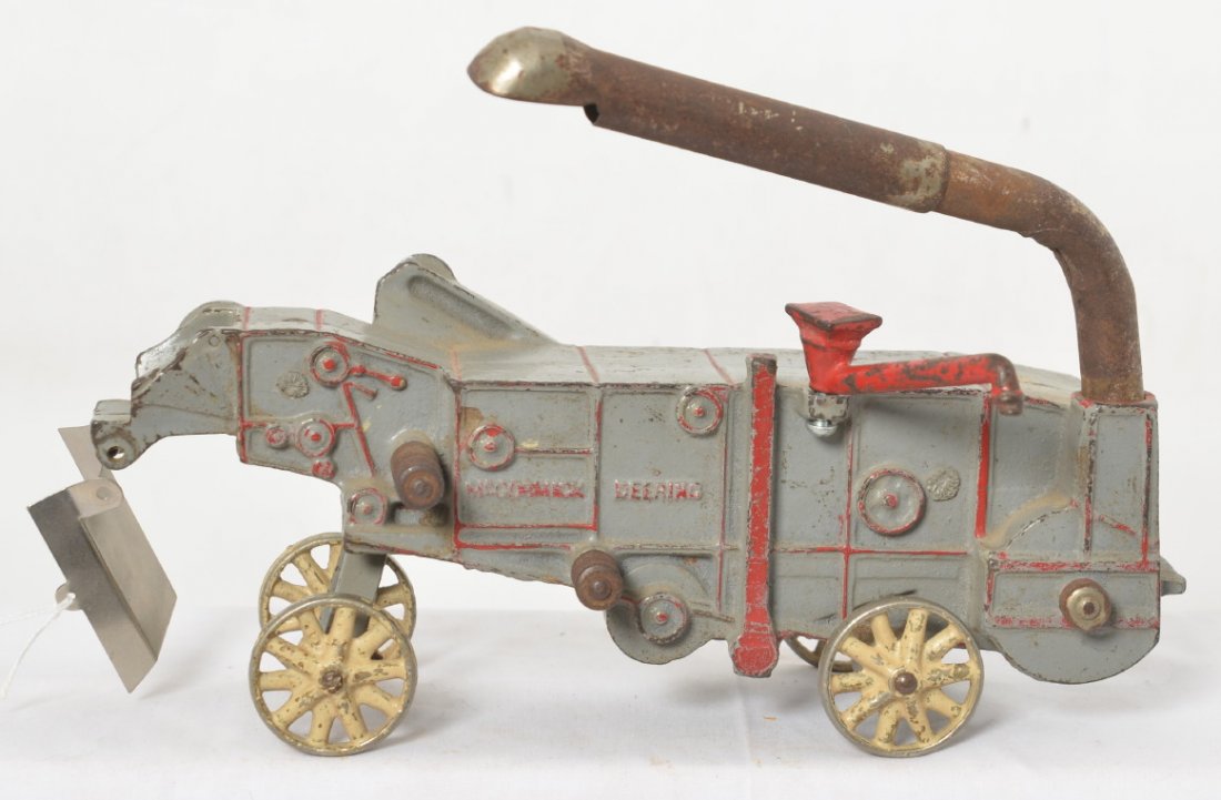 Arcade cast iron McCormick Deering threshing machine: Cast iron Arcade 451 McCormick Deering threshing machine toy. Toy appears to be in original paint/condition. Toy measures approximately 17-1/2 inches long.