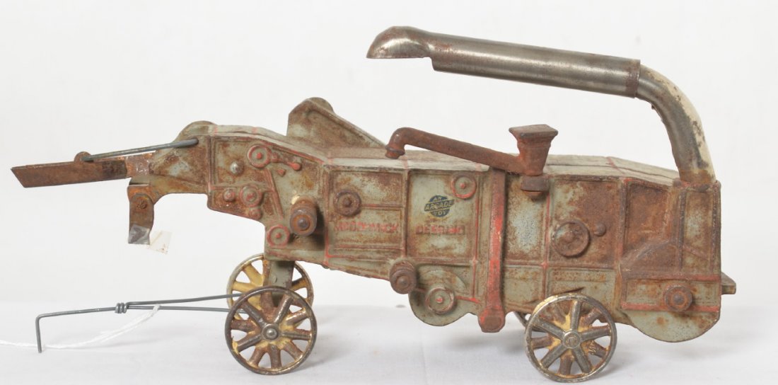 Arcade cast iron McCormick Deering threshing machine: Cast iron Arcade 451 McCormick Deering threshing machine toy. Toy appears to be in original paint/condition with surface rust. Toy measures approximately 17-1/2 inches long. Decal appears original.