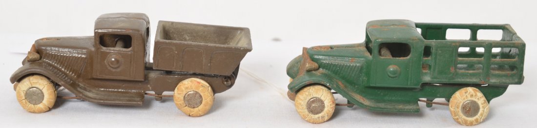 Two early cast iron trucks, one stake one dump: Two early cast iron trucks, one stake one dump. Trucks have piano wire holding axles in. Both appear to be older repaints. Both have original tires.