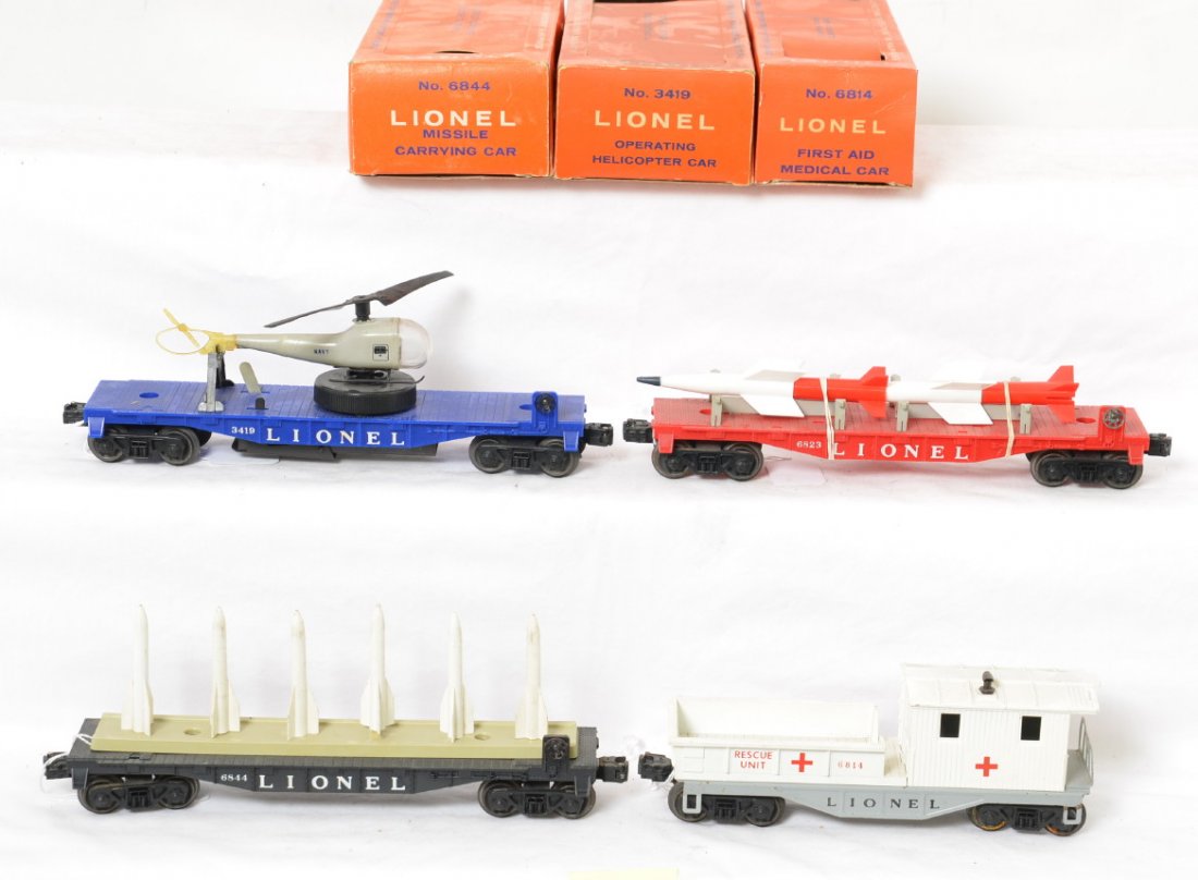 Lionel 3419, 6823, 6844, and 6814 w/three boxes: Postwar Lionel O gauge freight cars with original boxes, C6. 3419 helicopter launching car with Navy copter, 6823 flatcar w/rockets, 6844 flatcar w/missiles, and 6814 First Aid Medical Car caboose. 34