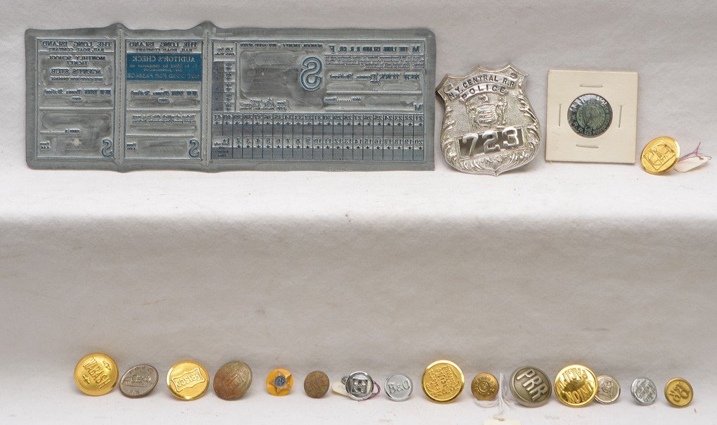 NYC RR Buttons Police Badge Ticket Print Press: Selection of Railroad buttons and a NY Central R.R. Police badge. Also included is a Long Island Railroad Co. metal printing press for tickets which measures 9 inches by 3 inches. Please view photo fo