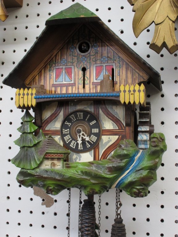 German 3-Weight Cuckoo Wall Clock: German 3-Weight Cuckoo Wall Clock, chalet and village motif with waterwheel, runs, chimes, music does not play consistently, some parts are missing, H. 12"