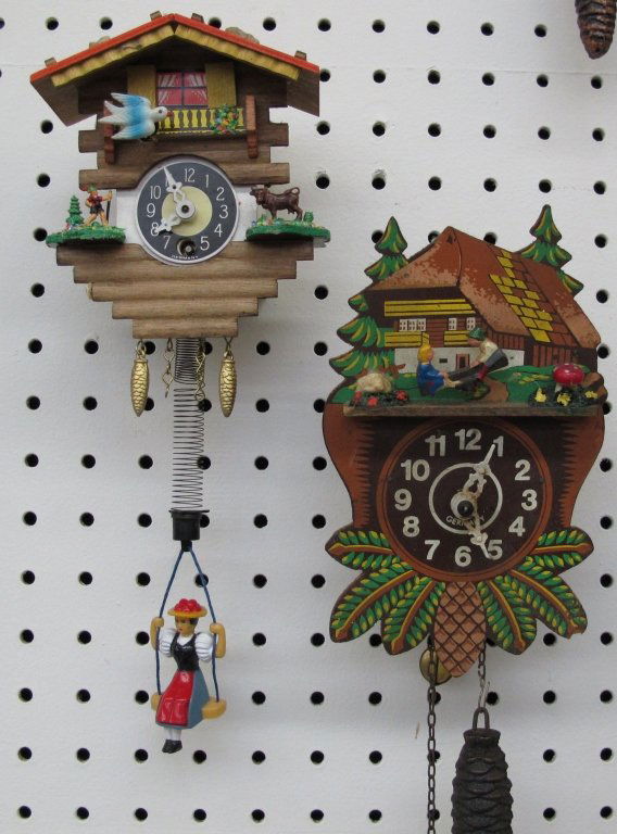 2 Novelty German Wall Clocks Running: 2 Novelty German Wall Clocks Running; House Motif with Girl bouncing on spring swing, H. 5" not including girl or decorative weights; House Motif with Children on Seesaw, seesaw works as clock ticks,