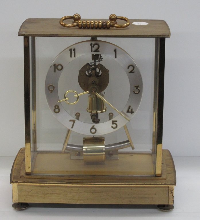 Brass and Glass German Case Clock: Brass and Glass Case Clock, running, H. 8", W. 7-5/8", D. 4-3/4", Dial 4-1/4", takes 4AA Batteries, dial is marked "Made in Germany", panel on inside marked "Howard Miller"