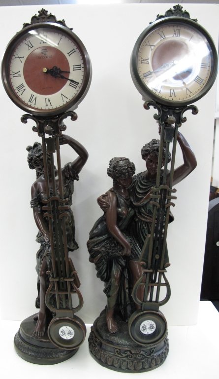 2 Reproduction Figural Swinger Clocks: 2 Reproduction Figural Swinger Clocks, quartz movements, running, H. 26-1/2" and 27-1/2"; please not that the composition of these clocks is a plastic which is made to look bronze, however they are no