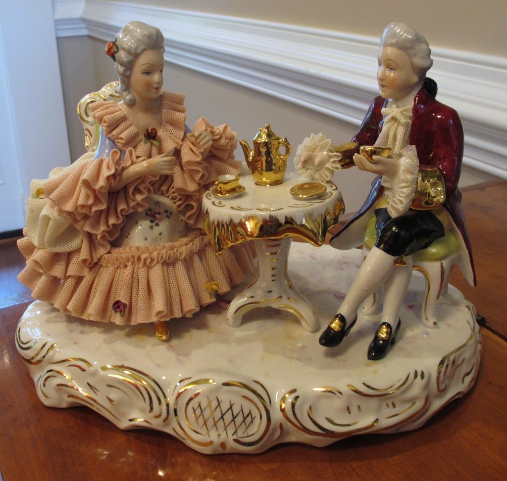 Porcelain Figurine-Lady and Gentleman having tea: Porcelain Figurine-Lady and Gentleman having tea at a table. Marked with a palate with an arrow in the middle and a crown on top.
