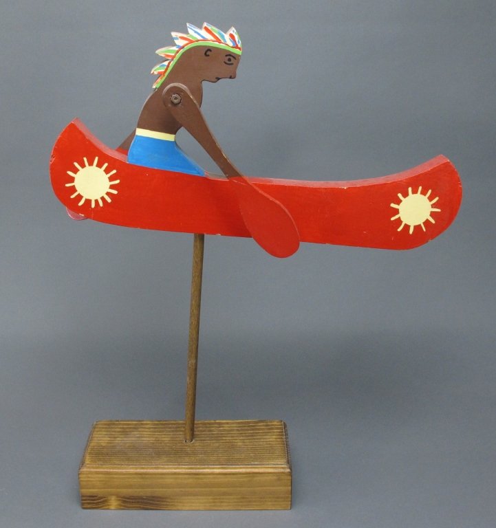 Painted Indian In Canoe Whirligig: Painted Indian In Canoe Whirligig / Whirlygig, painted wooden Indian figure paddles canoe, H. 19", label reads Gartell's Novelties, U.S. Route 7, Wilton, Conn