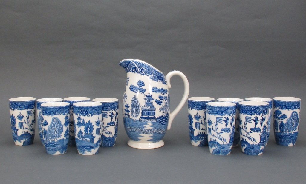 Blue Willow Pattern Pitcher and Tumblers: Blue Willow Pattern Pitcher and Glasses: Unmarked Pitcher, some crazing, H. 10" ; (12) Tumblers, some crazing, several with hairline cracks, H. 5-1/8"