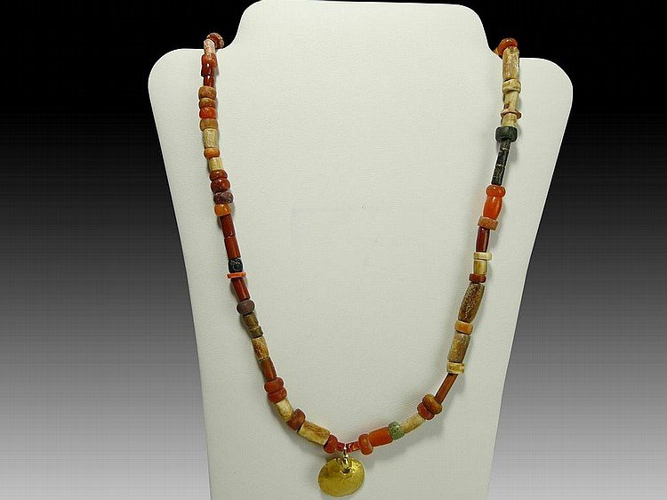 Tairona Necklace w/Gold Pendant: Pre-columbian Tairona Necklace, ca. 500-1500 A.D. Composed of a single strand of various shape and size carnelian stone beads with a flat repousse high gold content pendant (.625"). Modern Barrell cla