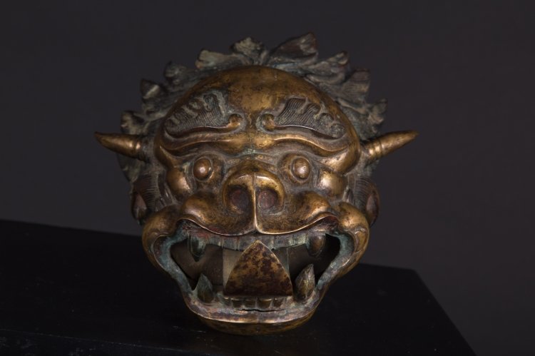 A dragon head: Nepal, early 20th Century A large embossed metal head with traces of gilding. It was probably an architectural element of a pagoda. l 30 cm
