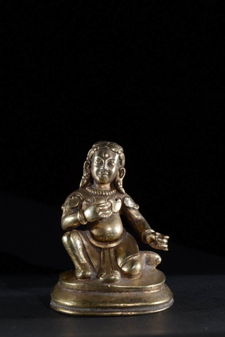A gilt bronze statuette: Nepal, 19th Century (?) A richly dressed kneeling figure. h 5,5 cm
