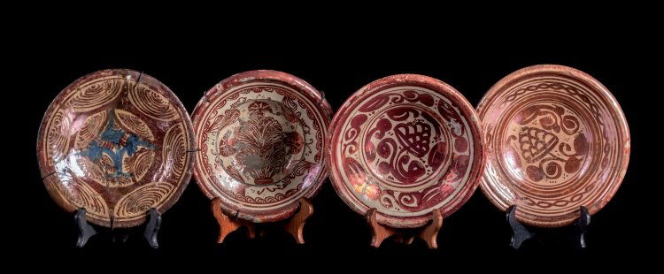 Four Hispanic-Moresque plates: Spain, Valencia (Manises), 17th - 18th Century Four small enamelled earthenware plates painted in ruby lustre and decorated with highly stylised vegetal and abstract elements. The exteriors are also d