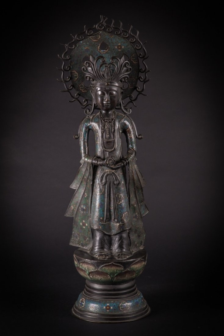 A bronze figure of Guanyin: China, Qing Dynasty, 19th Century The crowned deity is depicted in the act of lifting the Dharma scroll, he stands on a lotus flower pedestal and is exalted by a large halo that surrounds his head. A