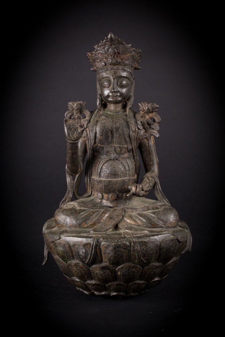 A bronze figure of Buddha: China, Ming Dynasty, 16th Century Heavy bronze cast with traces of original gilding and lacquer. The sculpture depicts Bhudda seated on a large lotus flower, decorated with three layers of overturned 
