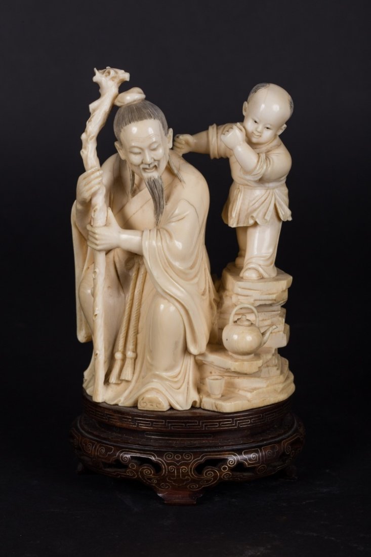 A figure of a sage with young boy: China, Qing Dynasty, 19th Century Elegant ivory intaglio depicting an elderly sage seated on a rock about to have tea. h 21 cm