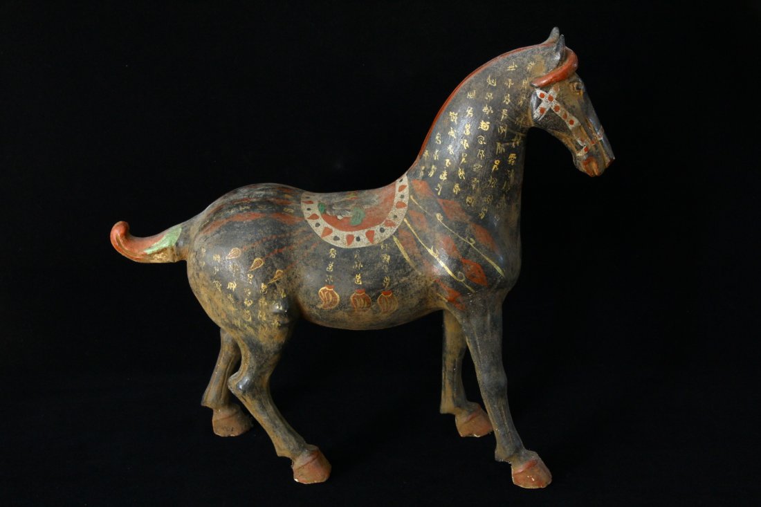Huge Chinese War Horse with Gilded Characters: An undated archaistic hollowed war horse in Tang Dynasty style with gilded chinese calligraphy painted on horse. The saddle is also beautifully painted. H: 16inc (41cm) L: 18inc (46cm). From the estat
