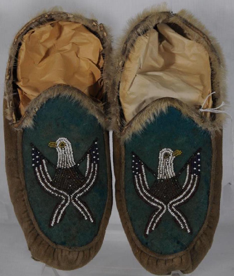 PAIR OF BEADED MOCCASINS C. 11" L, MOOSE HIDE?: WITH PUCKERED TOE. MOOSE FUR? AROUND ANKLE OPENING. INSTEP: AMERICAN EAGLE HEAD WITH 2 U.S. STREAMER FLAGS BEAD APPLIQUE ON BLUE FELT. CLOTH LINED. SUBARCTIC.
