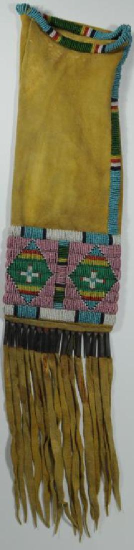 CROW DOUBLE DIAMOND PIPE BAG HAND SEWN (SINEW?): WITH WHITE, BLACK, BLUE, RED, AND GREEN BEADS ON PINK BEAD GROUND, 16 TIN CONES ATTACHED TO LEATHER EXTENSIONS, BEADS EXTEND UP SIDE AND AROUND TOP, BAG 13" L X 5" W, FRINGE EXTENSIONS 9" L, CA. 20TH