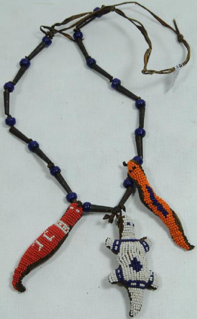 NATIVE AMERICAN FETISH NECKLACE RAWHIDE NECKLACE,: CONSISTS OF BLACK BEADS INTERSPERSED BETWEEN TIN CONES WITH THREE UMBILICAL CORD FETISHES, FETISHES ARE: BEADED SNAKE, LIZARD, AND TURTLE, FETISHES ARE HAND SEWN WITH SINEW DESIGN ON EACH FETISH, CA. 