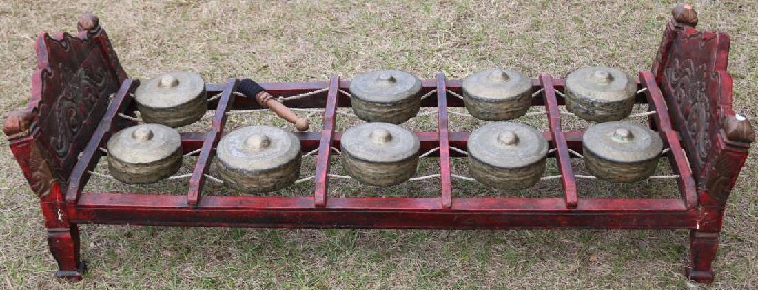 20TH C. TIBETAN GONG ON CARVED AND PAINTED BED: FORM BASE, 9 GONGS, ONE MISSING, 17"H X 54"L X 21"W