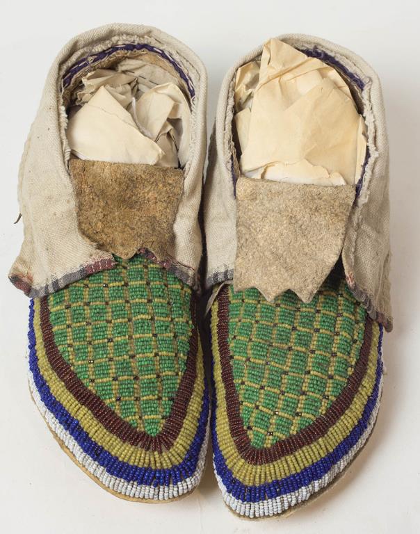 19TH C. NORTHERN PLAINS MOCCASINS, BEADED IN: YELLOW AND GREEN SQUARES, WITH RED, YELLOW, BLUE AND WHITE BORDERS, SINEW SEWN ON BUFFALO HIDE, C. 1890, CANVAS TOPS, PROBABLY BLACKFEET OR CROW. 9 1/2" L, APPROX. 3 1/2" W, SMALL SECTION OF WHITE BEA
