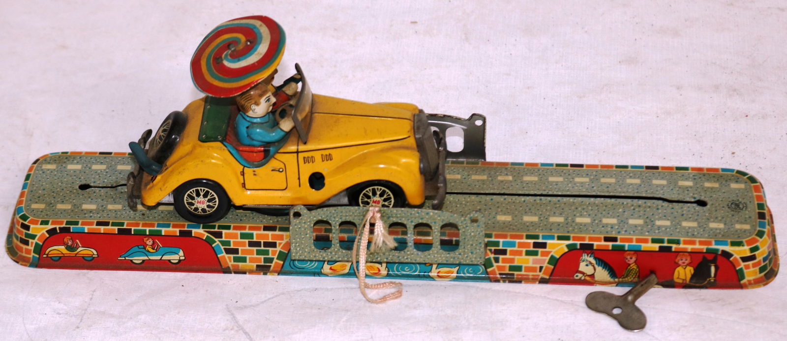 JAPANESE WIND UP LITHO TIN TOY MG ON BRIDGE WITH: KEY, WORKING CONDITION APPROX 12" L GOOD OVERALL CONDITION, WITH ORIGINAL BOX