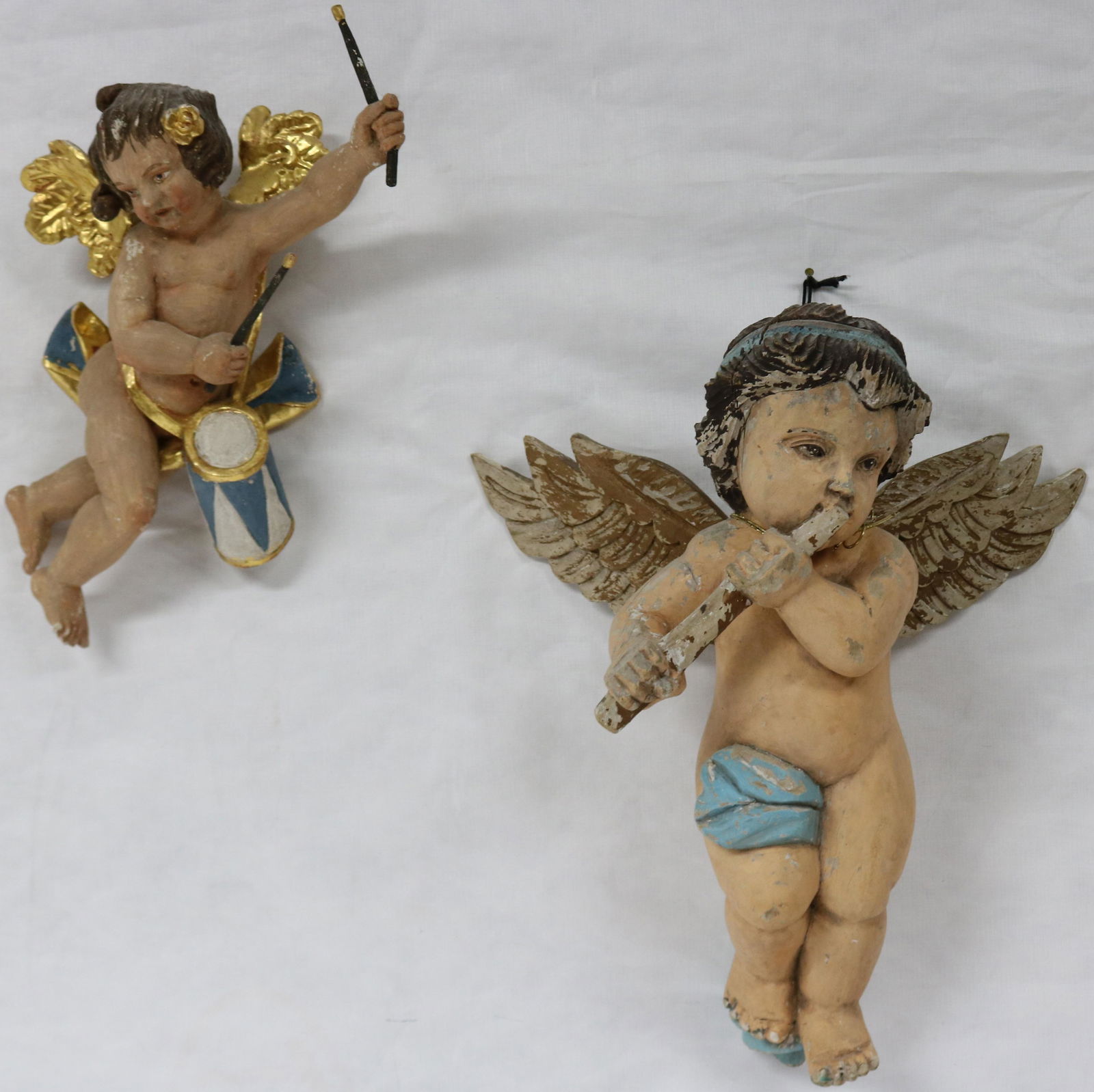 20TH C. TWO CARVED WOODEN CHERUBS WITH: INSTRUMENTS, INCLUDING 18" X 15" WIDE FLUTE CHERUB SHOWS OVERALL PAINT LOSS, 17" CHERUB WITH, DRUM WITH, GOLD HIGHLIGHT