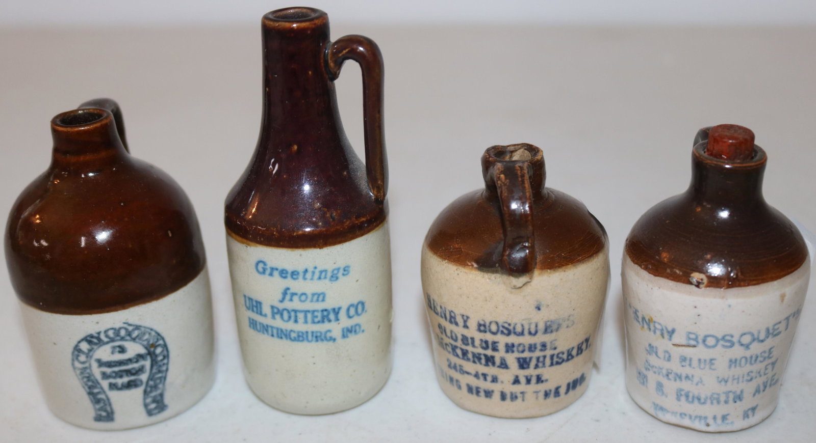 4 BROWN & WHITE MINIATURE STONEWARE ADVERTISING: JUGS, GOODS COMPANY 73? ST. BOSTON MA. 3" H, GREETINGS FROM UHL POTTERY HUNTINGBURG IND. 3 7/8" H, 2 HENRY BOSQUET'S OLD BLUE HOUSE, MCKENNA WHISKEY LOUISVILLE KY, 2 1/2" H