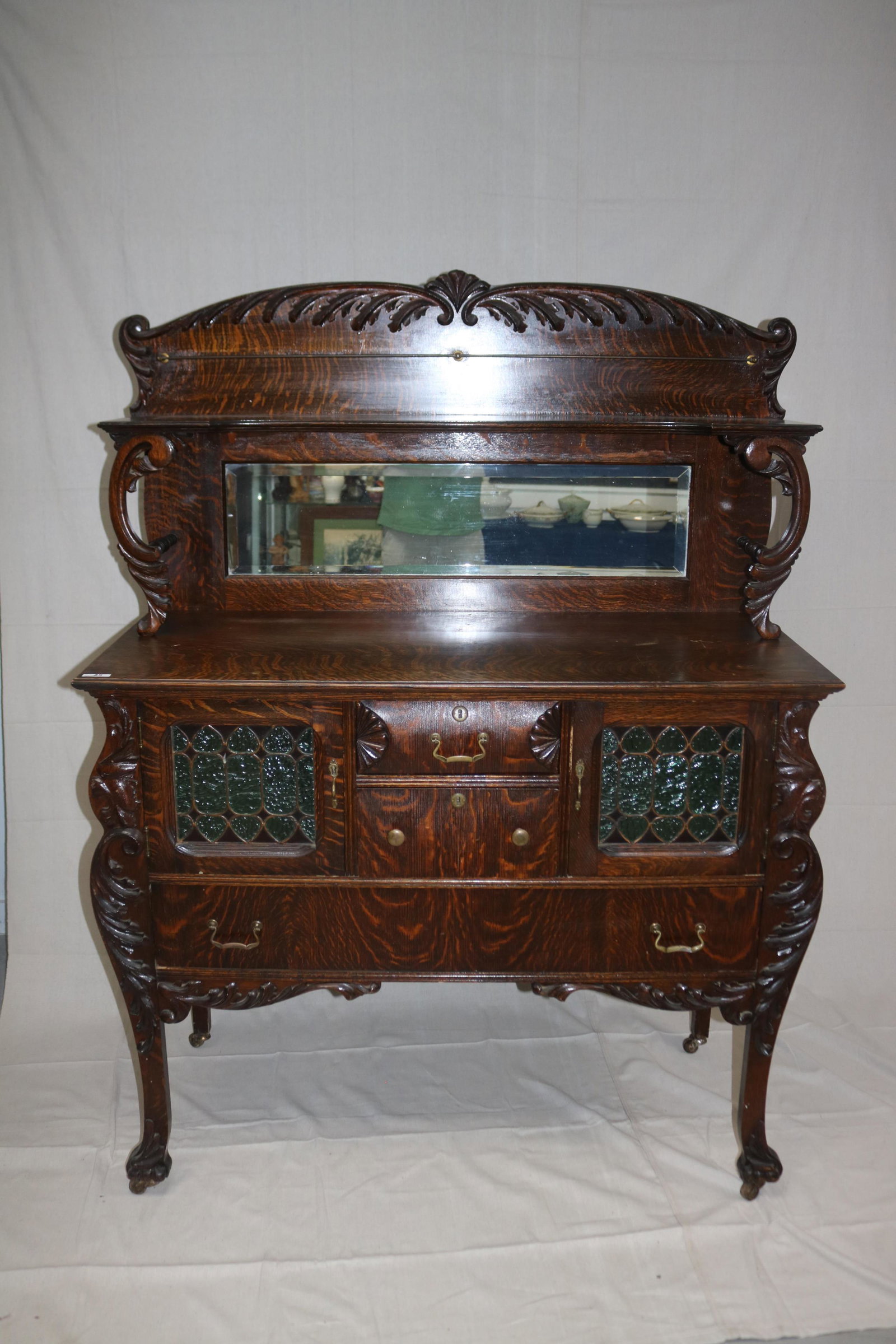 EXCEPTIONAL QUARTER SAWN OAK SIDEBOARD: WITH CLAW FEET, LEADED DOORS, MIRRORED GALLERY AND BRASS PULLS, 65" H. 48" W. 21 1/4" D.