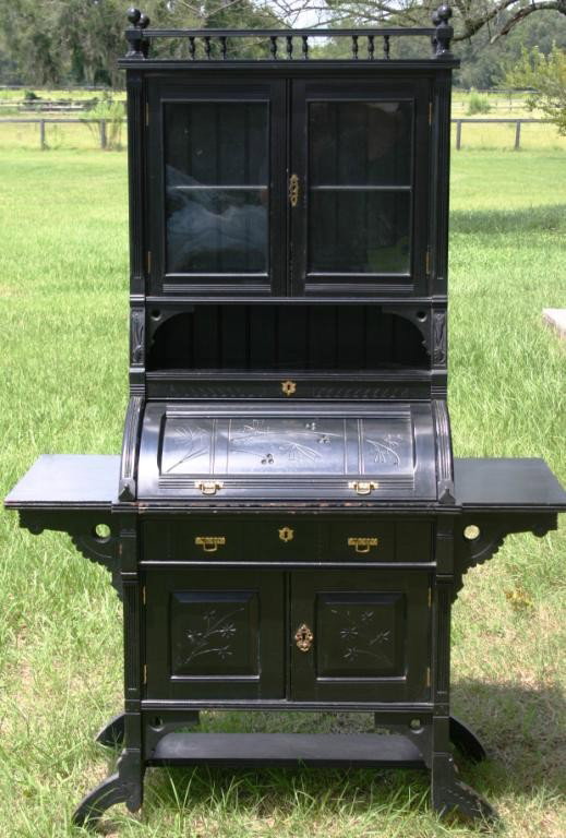 VICTORIAN AESTHETIC MOVEMENT EBONIZED LADIES DESK,: WITH CYLINDER ROLL FRONT, GLAZED TOP DOORS, AND WRITING WINGS, 67" H, 46" W, 20" D