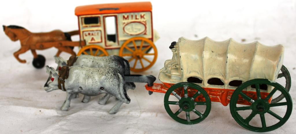 TWO CAST METAL ANIMAL DRAWN VEHICLES,: BY BARCLAY TO INCLUDE OXEN DRIVEN CONESTOGA WAGON, AND HORSE DRIVEN MILK WAGON WITH SOME PAINT LOSS, 2 1/2" H, 5" - 7" L