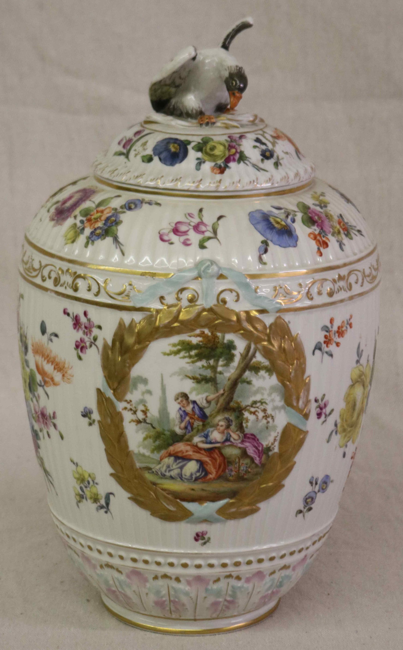 19TH C. K.P.M. GERMAN PORCELAIN COVERED JAR, LID: WITH BIID FINIAL, PROFESSIONAL REPAIR TO 1 WING, OVERALL FLORAL DECORATION WITH PANELS OF COURTING COUPLES, 16" H, 9 1/2" DIA., BLUE SCEPTER MARK