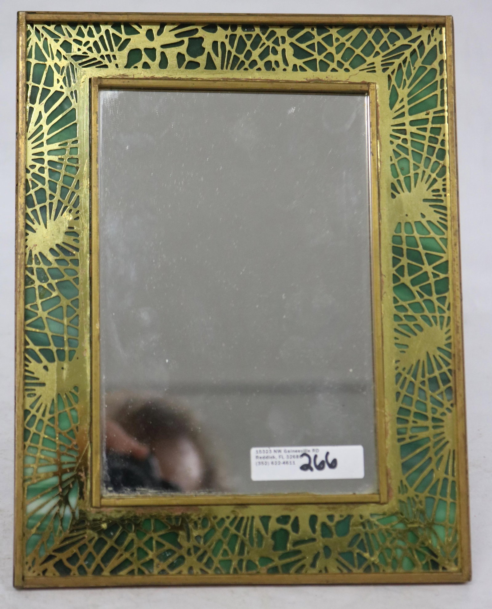 TIFFANY STUDIOS PINE NEEDLE FRAME MOUNTED WITH: MIRROR, INSET GREEN SLAG PANELS, SHOWS OLD REPAIR TO GLASS INSERTS, 9" X 7"
