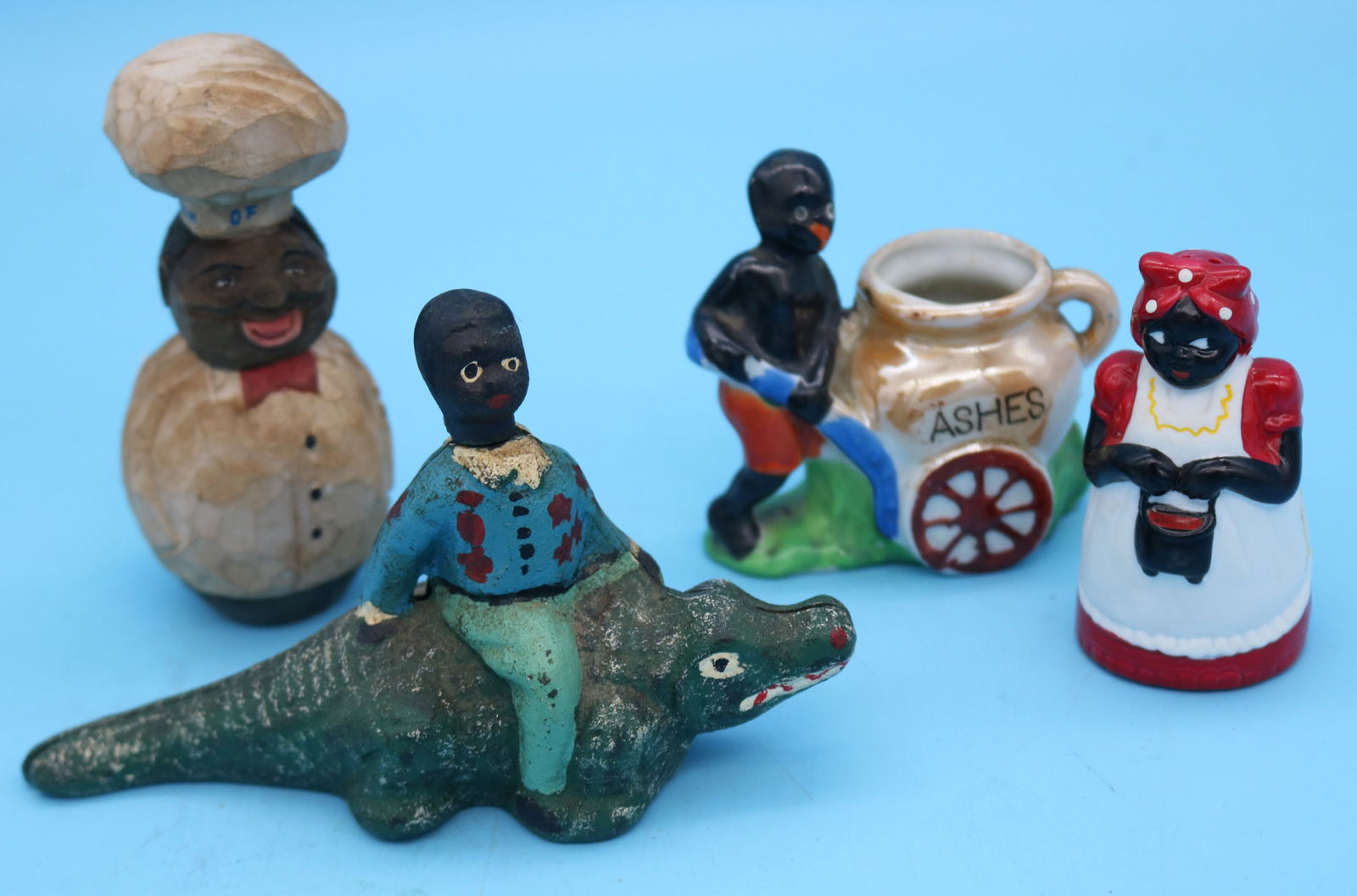 LOT OF 4 BLACK MEMORABILIA ITEMS, CAST IRON: FIGURE ON ALLIGATOR 3 1/4" H, 6" W, LATE 20TH C. CARVED WOOD CREAM OF WHEAT CHEF 4 1/2" H, PORCELAIN FIGURE WITH ASH CART 3" H, PORCELAIN SALT SHAKER 3" H