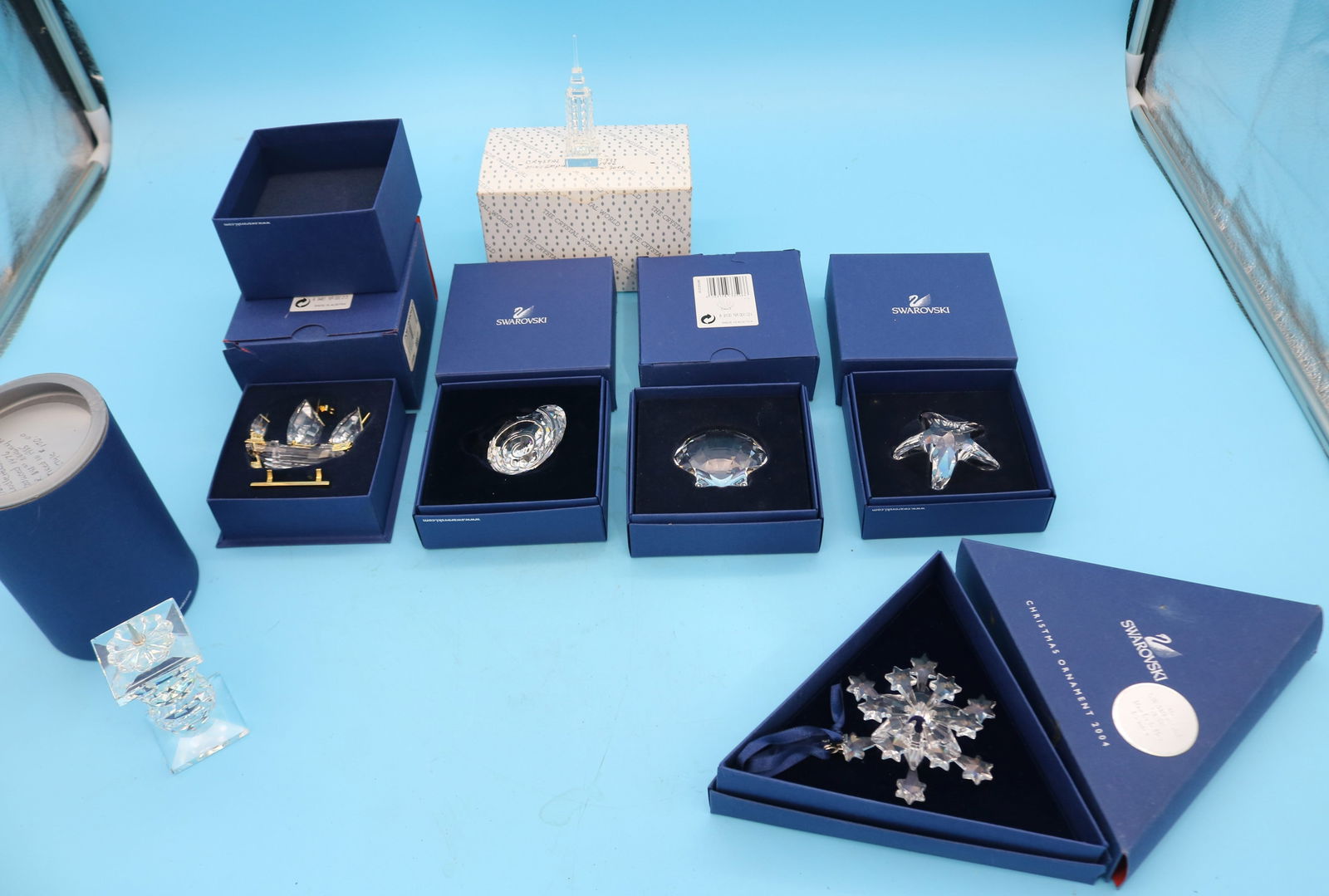 7 SWAROVSKI CRYSTAL ITEMS IN ORIGINAL BOXES,: SHIP, SHELLS, STAR FISH, SNOW FLAKE, EMPIRE STATE BUILDING