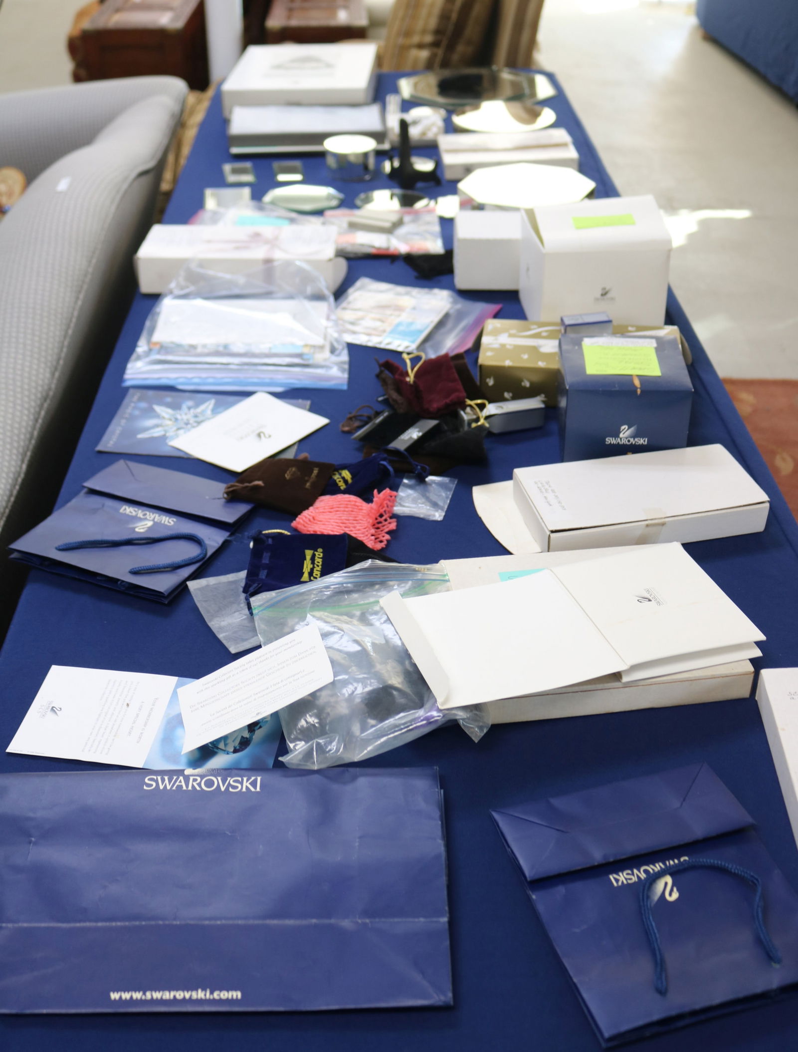 8' TABLE LOT OF SWAROVSKI CRYSTAL, PLATFORMS,: PAPERWORK, GLOVES, VCR TAPE, ETC.